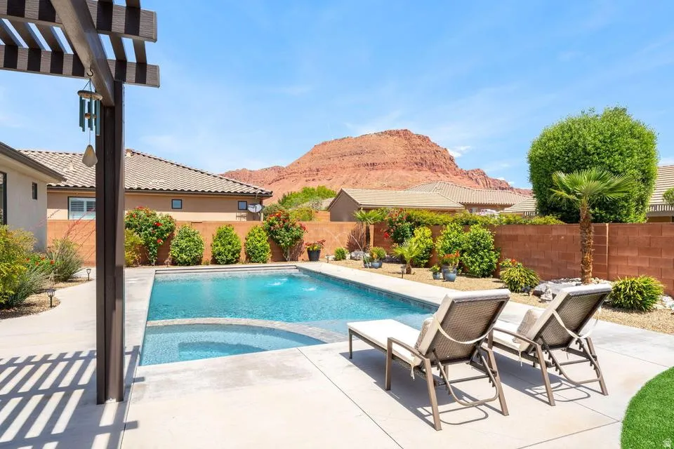 Combined pool / hot tub featuring a patio area, a pergola, a fenced backyard, and a mountain view
