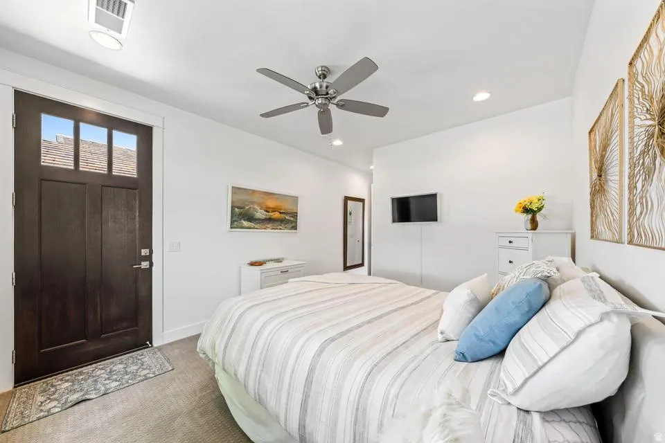 Bedroom with light carpet, ceiling fan, and recessed lighting