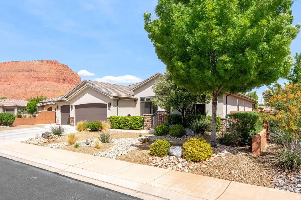View of front of property featuring stucco siding, an attached garage, driveway, a mountain view, and stone siding