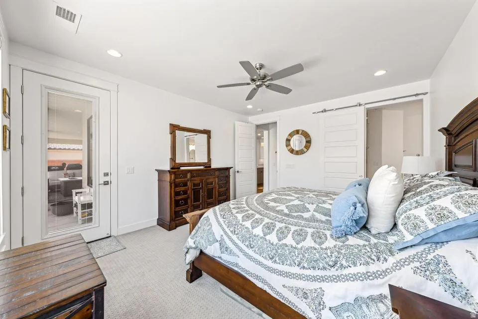 Bedroom with a barn door, light carpet, ceiling fan, access to exterior, and recessed lighting