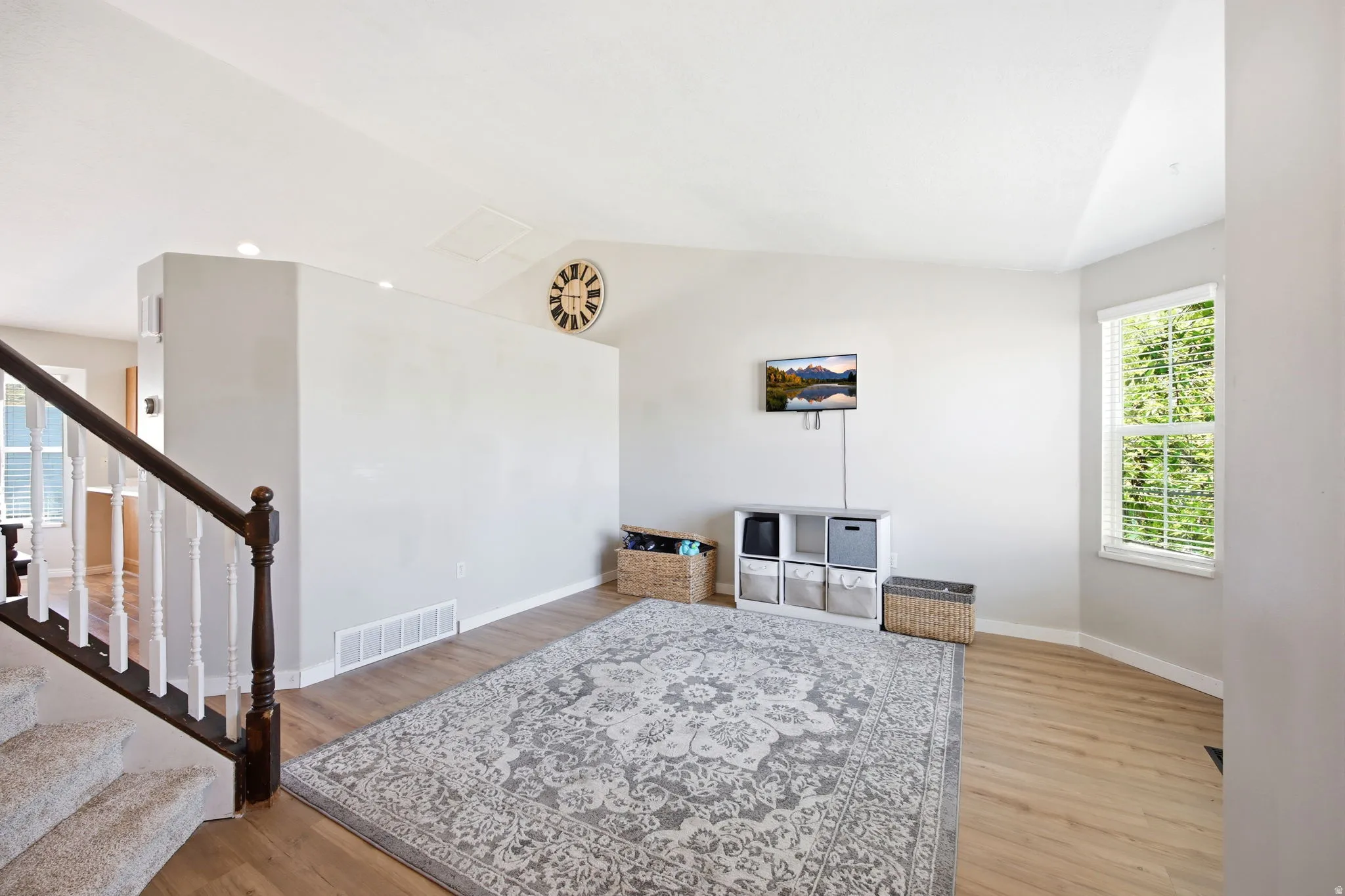 Living area with plenty of natural light, light wood finished floors, and lofted ceiling