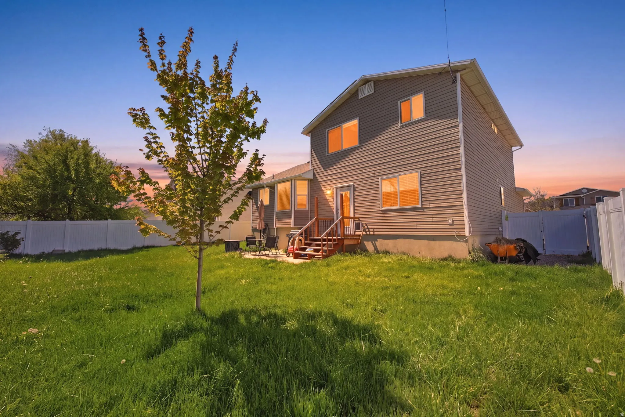 Back of house at dusk featuring a fenced backyard and a gate