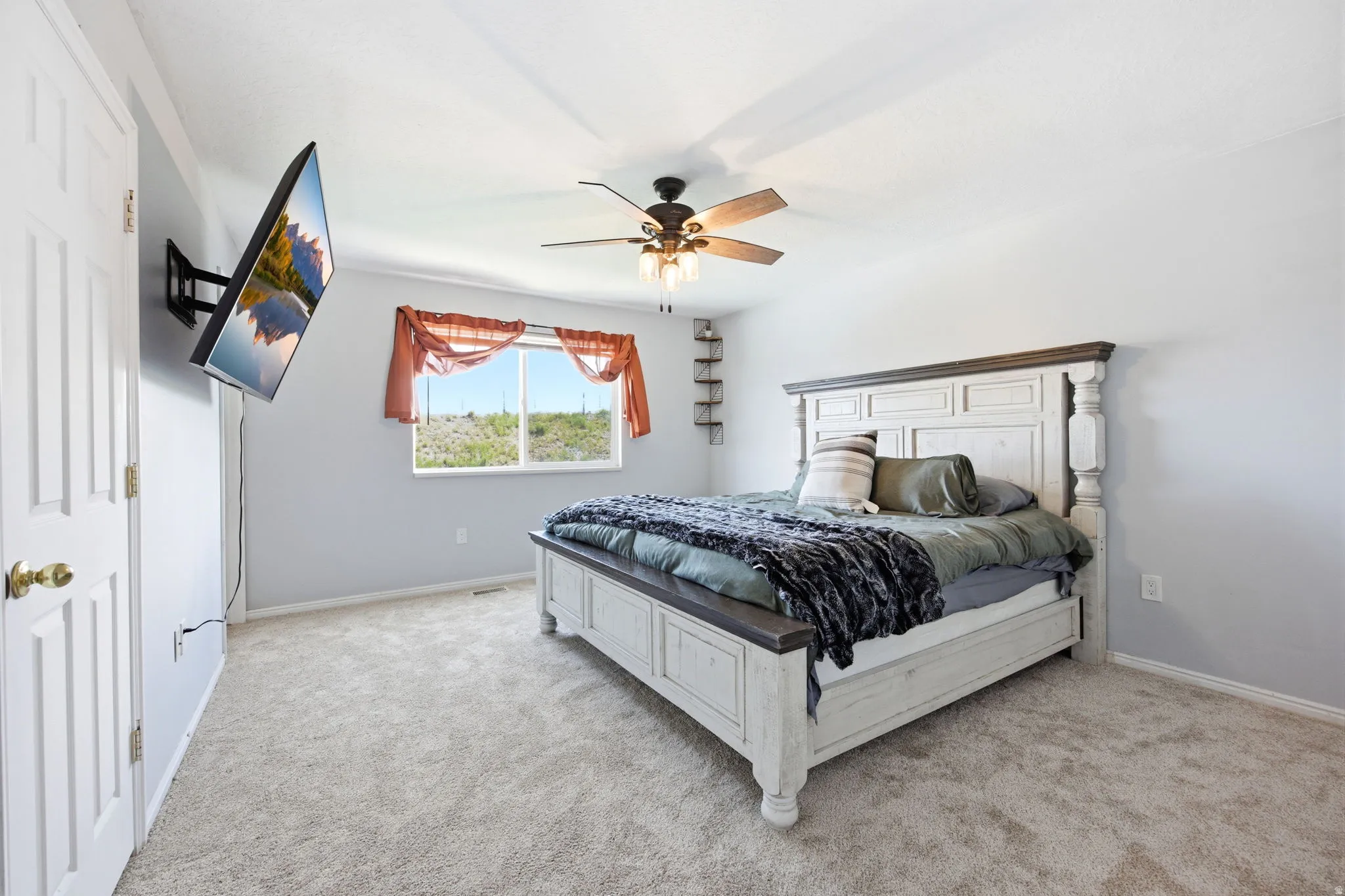 Bedroom with light colored carpet and a ceiling fan