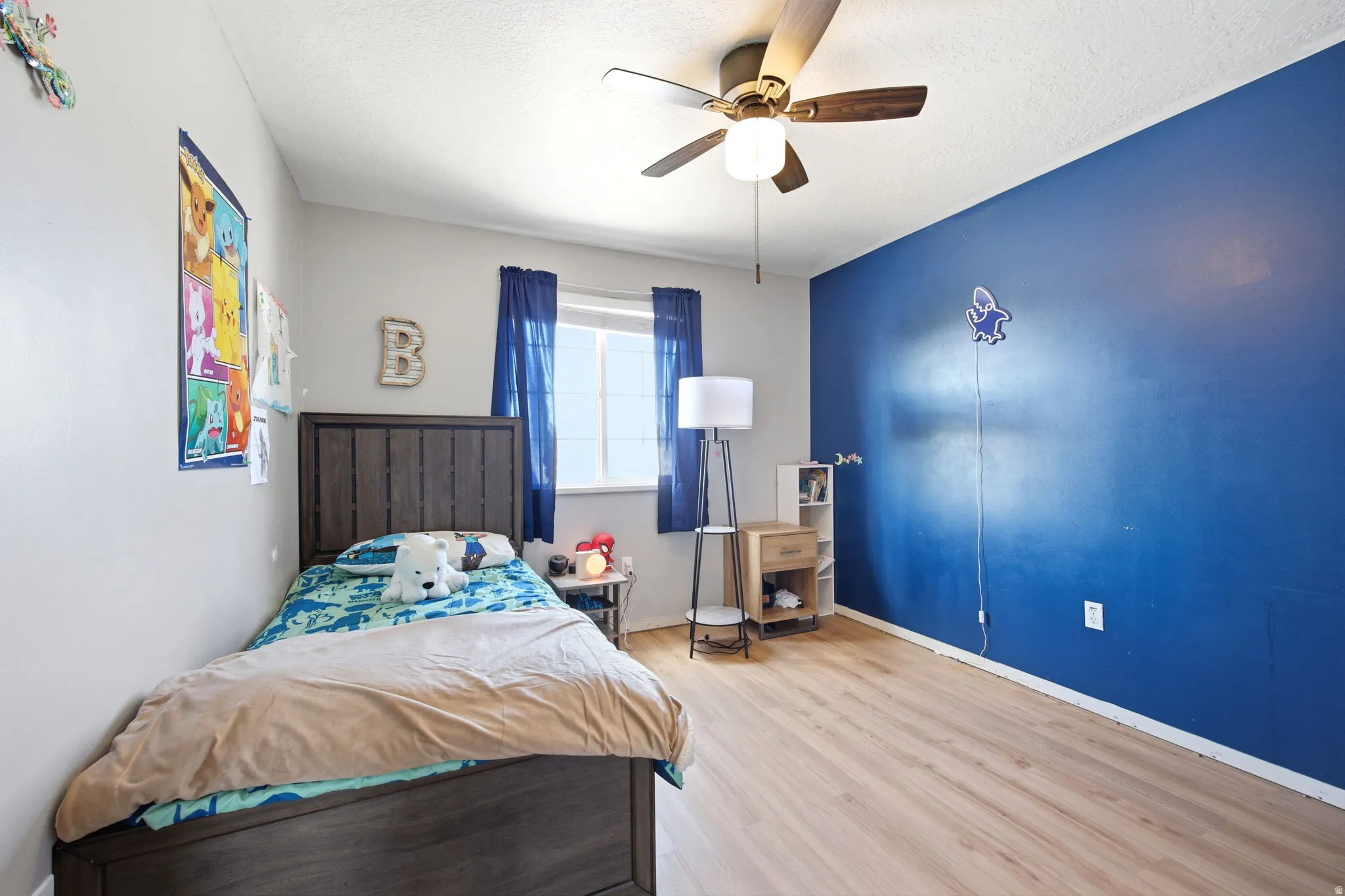 Bedroom featuring light wood-style floors, a ceiling fan, and a textured ceiling