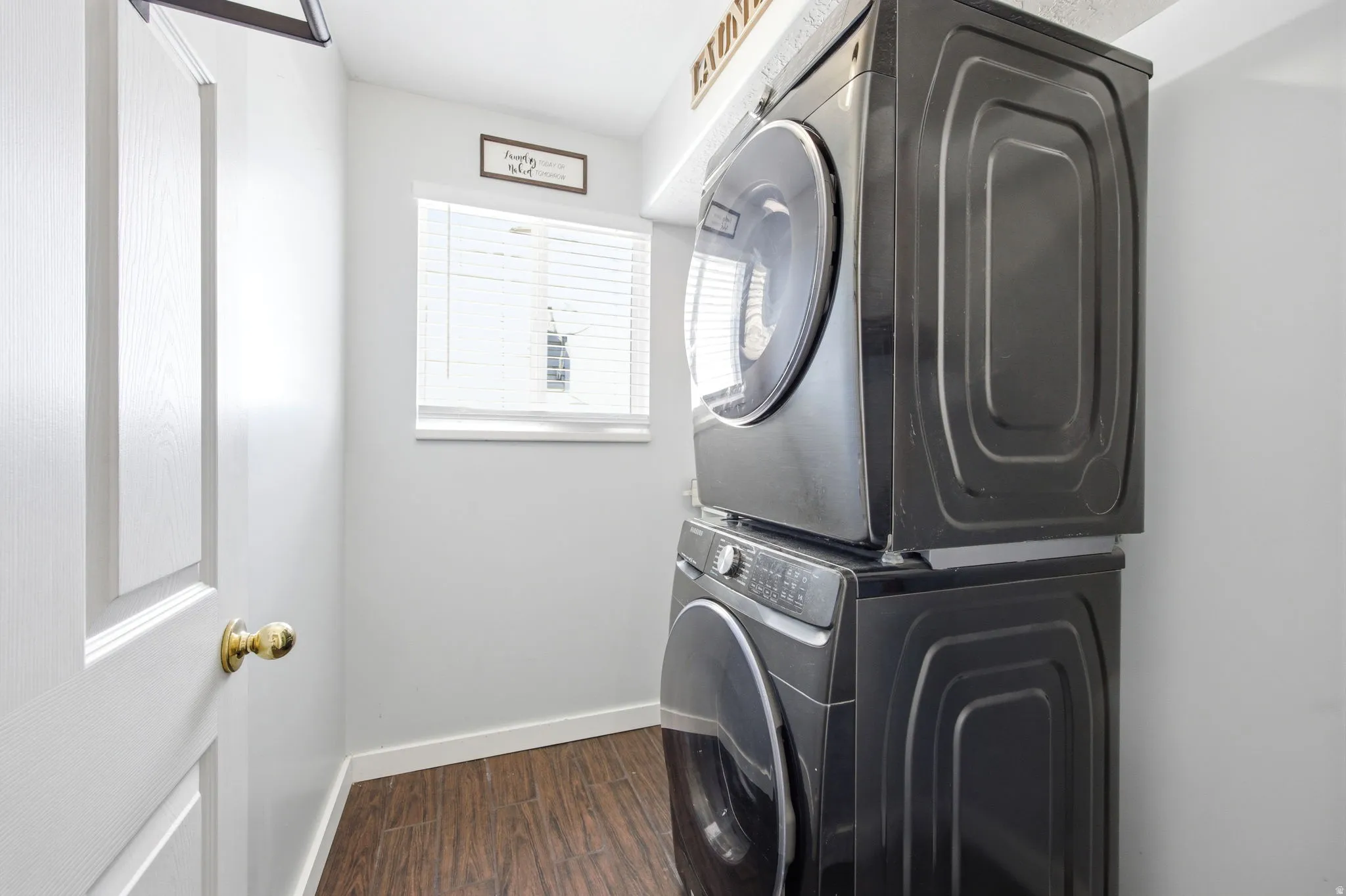 Laundry room featuring stacked washer and dryer and dark wood-style floors
