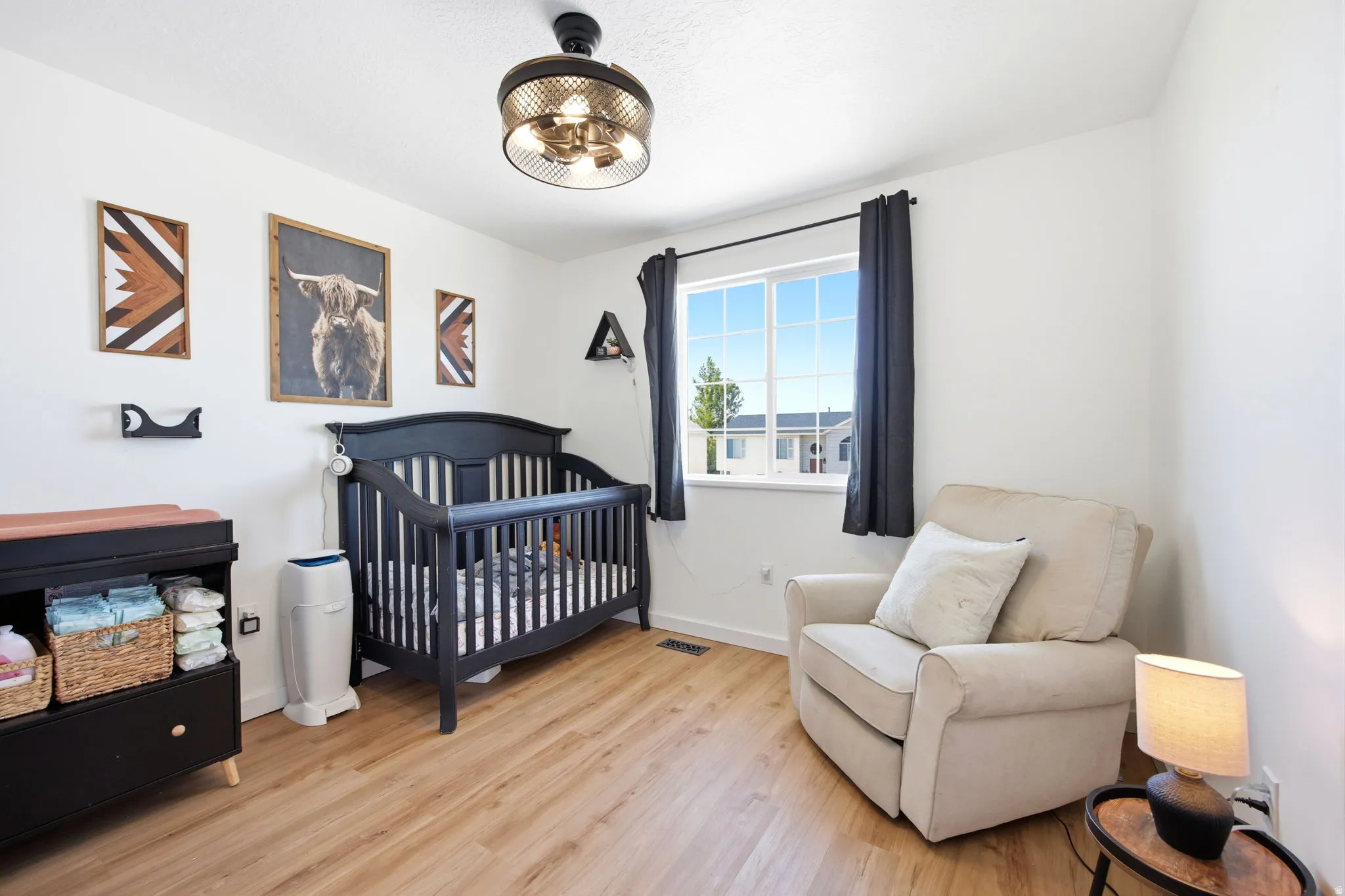 Bedroom with a nursery area and light wood-style floors