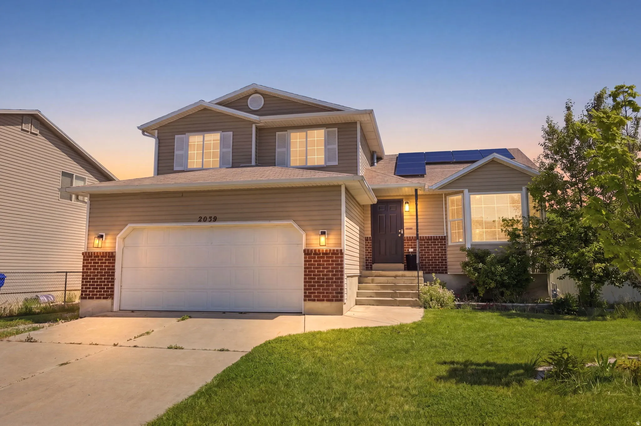 Traditional home featuring solar panels, brick siding, driveway, and a lawn