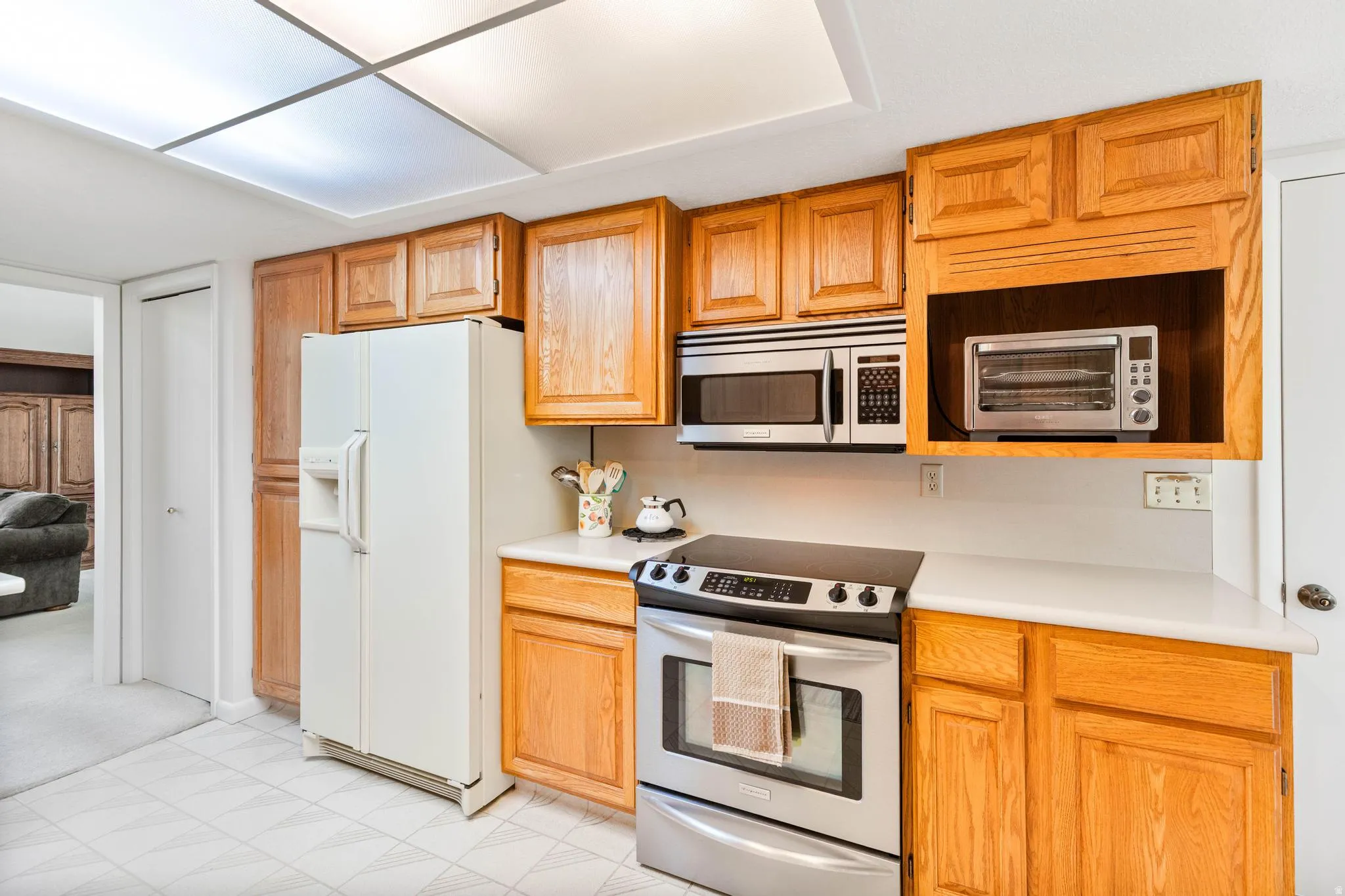 Kitchen with stainless steel appliances, light countertops, and wood finish cabinets