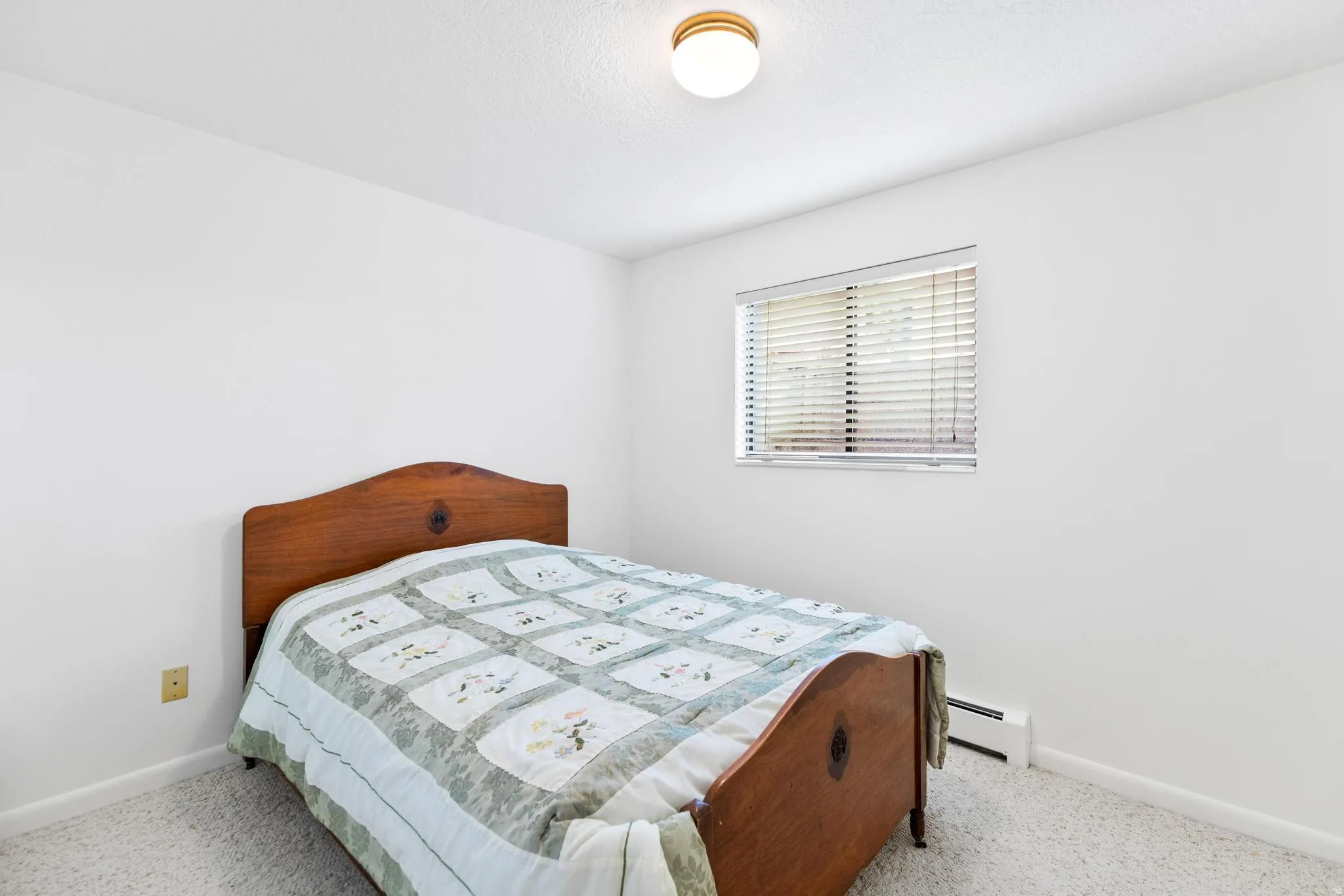 Bedroom with baseboard heating and light carpet