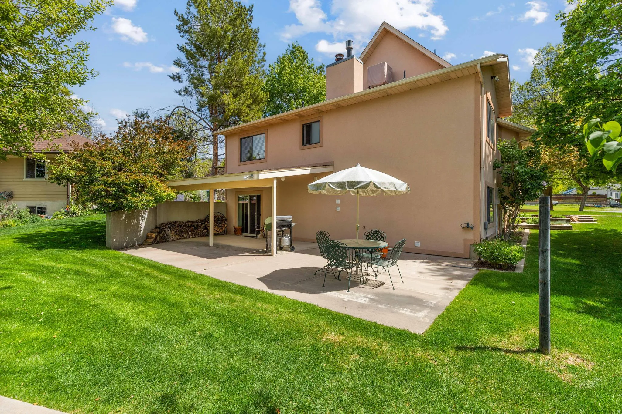 Rear view of property with a lawn, stucco siding, a patio, and a chimney