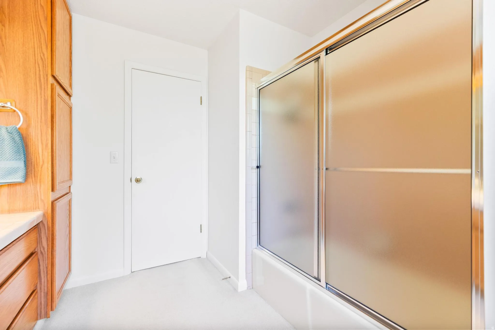 Full bath with vanity, shower / bath combination with glass door, and light carpet