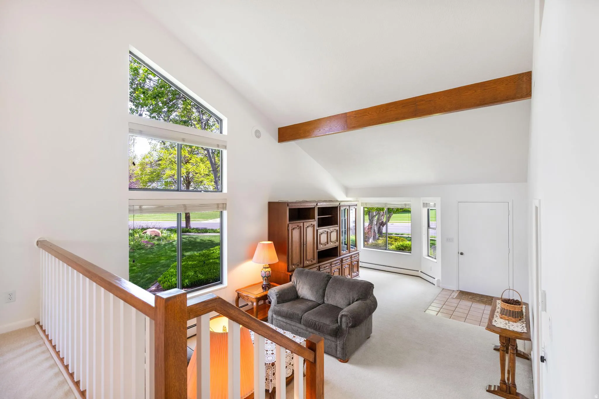 Living area featuring light carpet, a baseboard heating unit, and lofted ceiling