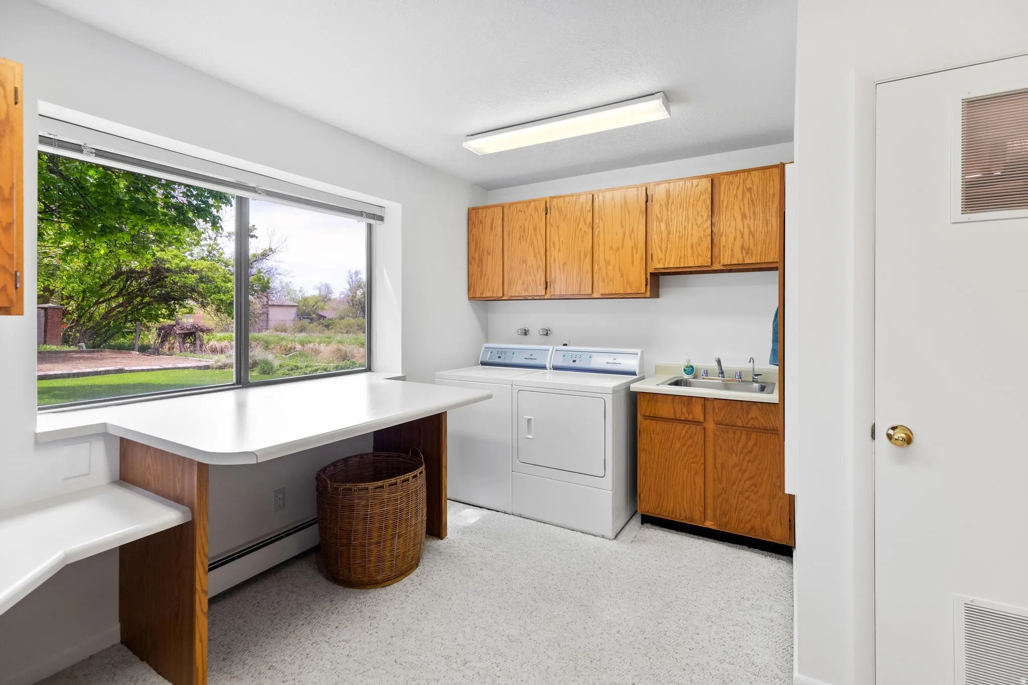 Laundry room with washing machine and dryer, a baseboard radiator, and cabinet space