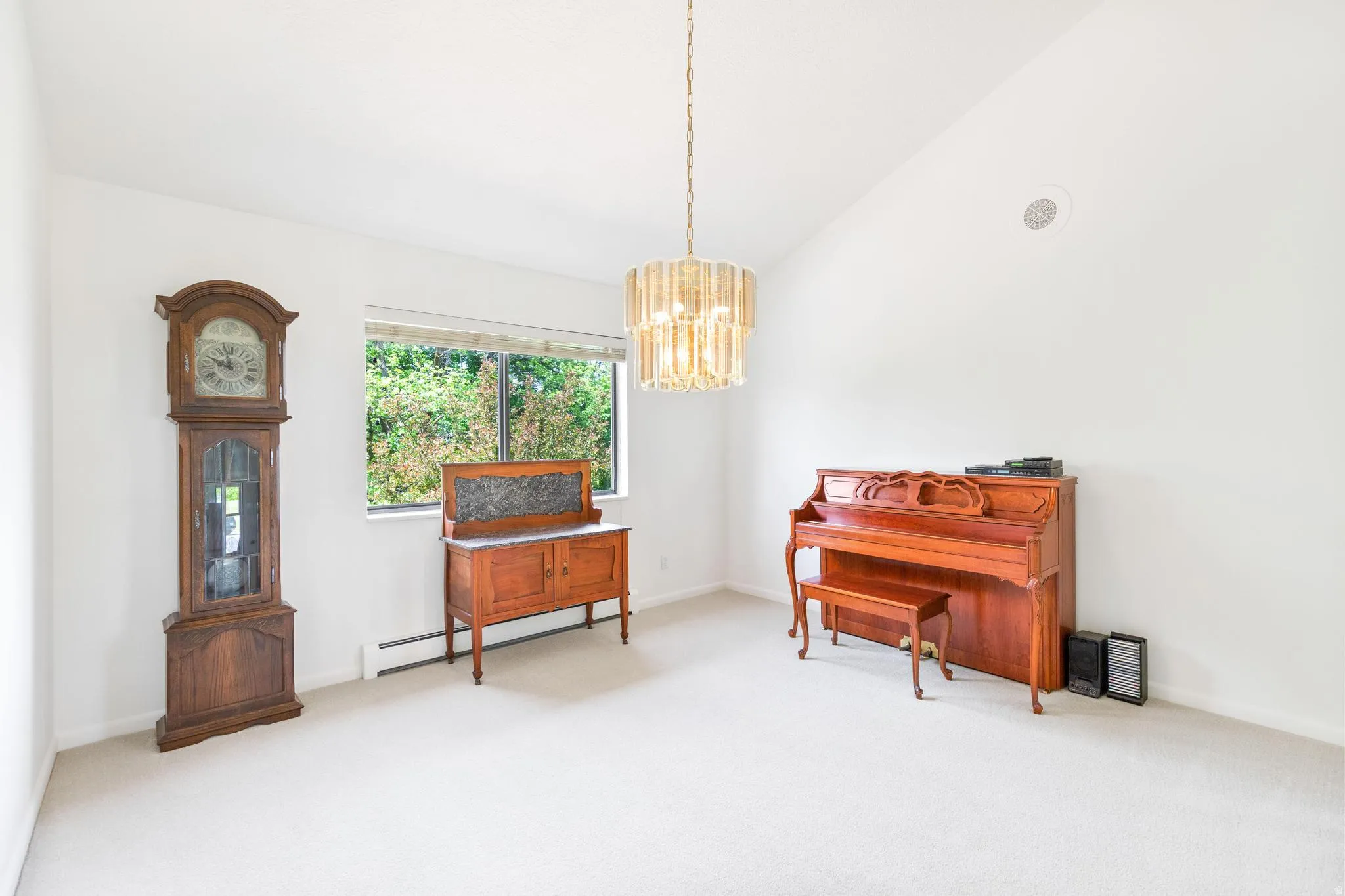 Living area with light colored carpet, lofted ceiling, a baseboard heating unit, and a chandelier