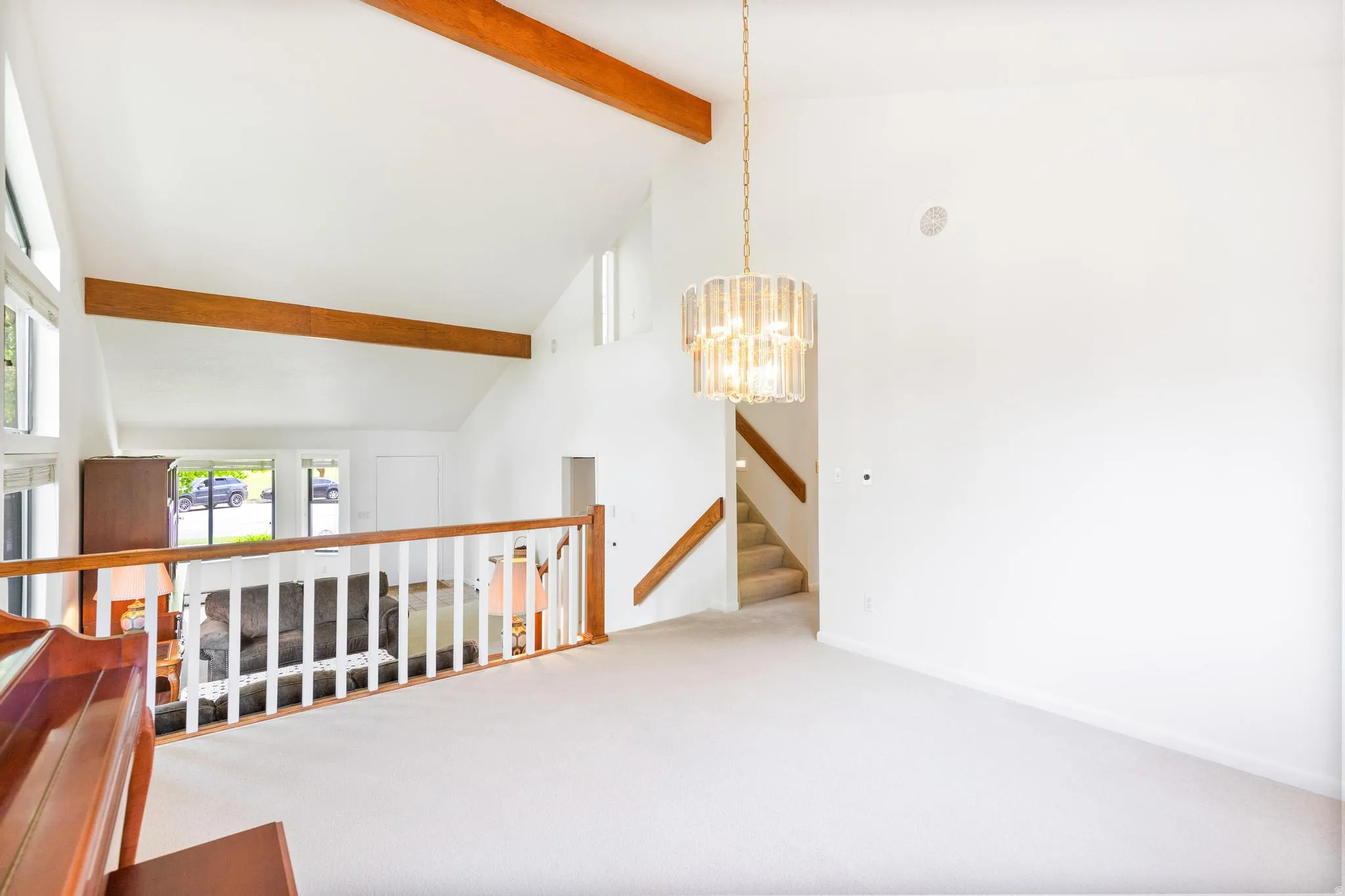 Hallway with carpet floors, lofted ceiling, and a chandelier