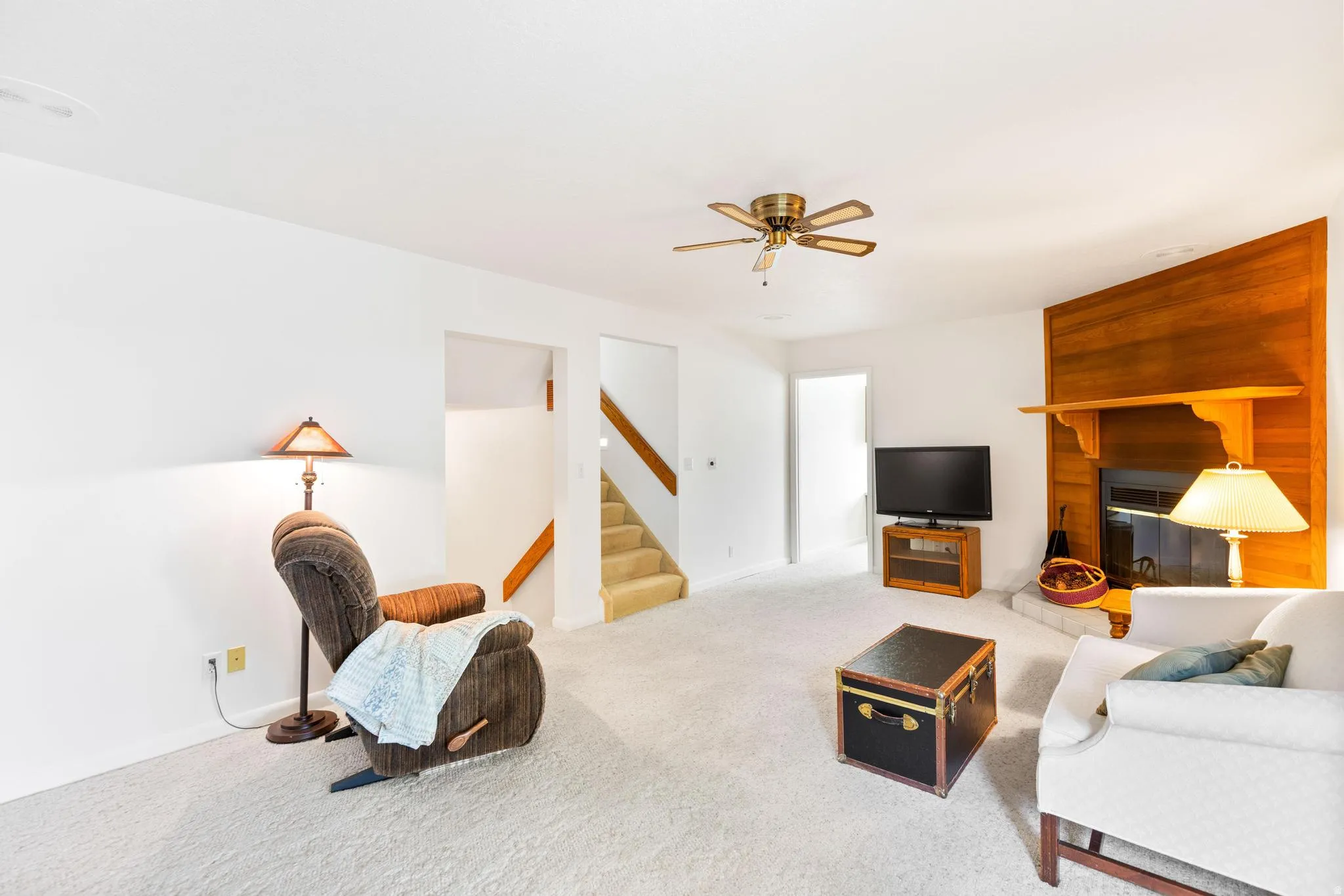 Carpeted living room with a ceiling fan and a fireplace