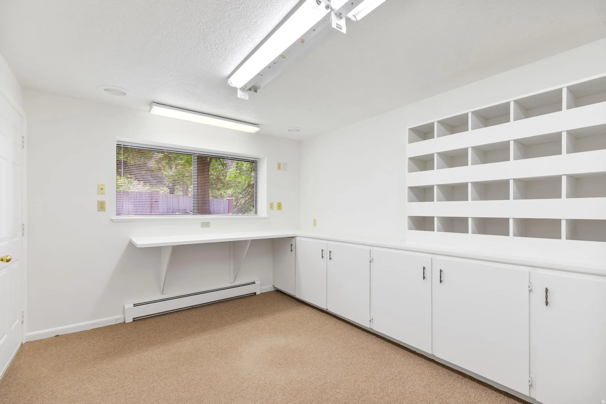 Spare room featuring a baseboard radiator, light colored carpet, and a textured ceiling