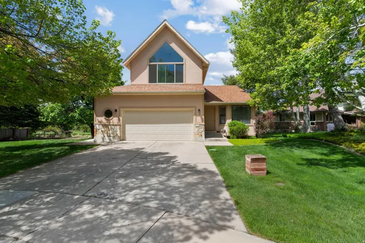 Traditional-style house with a garage, a front yard, stucco siding, concrete driveway, and stone siding