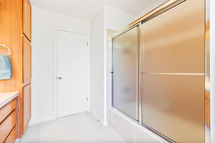 Full bath with vanity, shower / bath combination with glass door, and light carpet