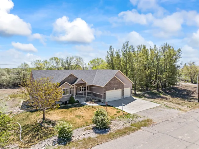 View of front of house featuring a porch, concrete driveway, a garage, a shingled roof, and brick siding