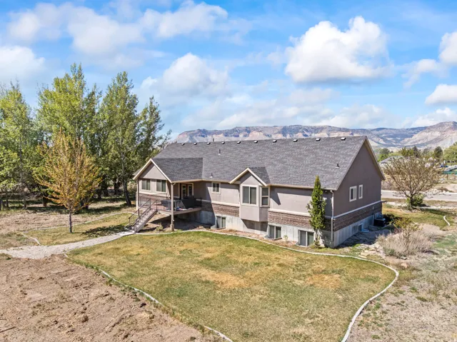 Rear view of house featuring roof with shingles, a yard, and a mountain view