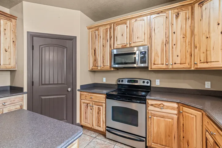 Kitchen featuring stainless steel appliances, dark countertops, and light tile patterned flooring