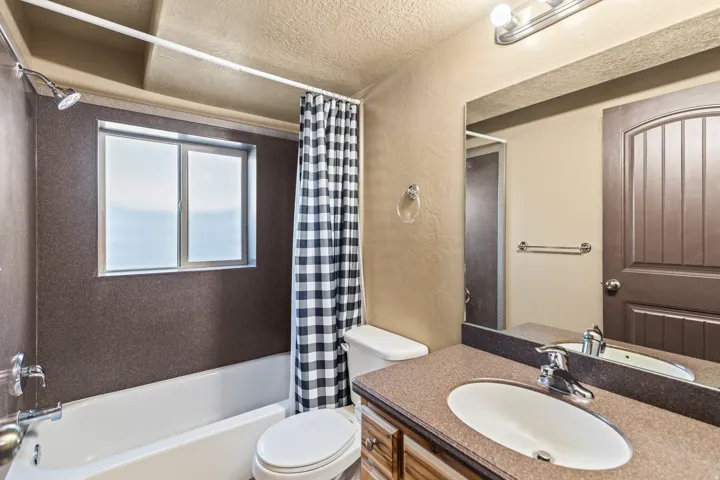 Full bathroom with a textured wall, a textured ceiling, vanity, and shower / bathtub combination with curtain
