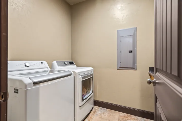 Laundry area featuring a textured wall, electric panel, and independent washer and dryer