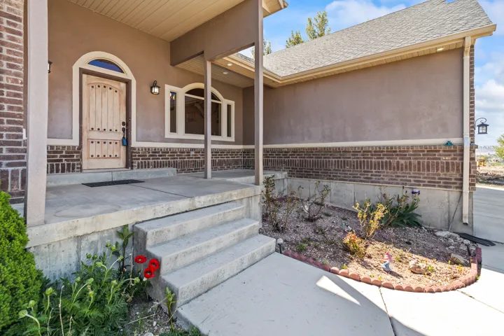 Property entrance featuring roof with shingles, brick siding, and stucco siding