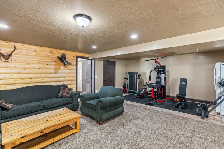 Exercise room featuring a textured ceiling, rustic walls, carpet floors, and recessed lighting
