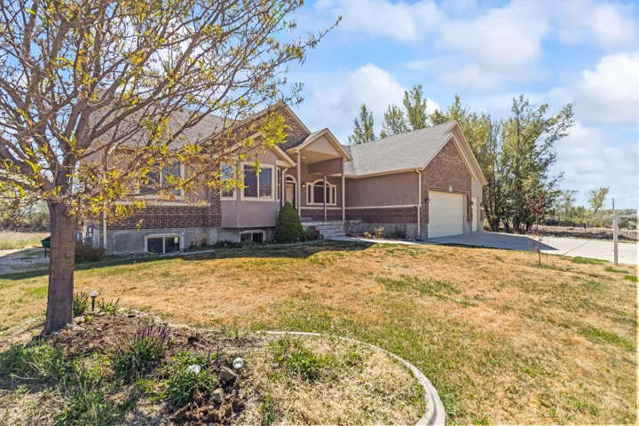 View of front facade featuring brick siding, a front yard, a garage, and driveway