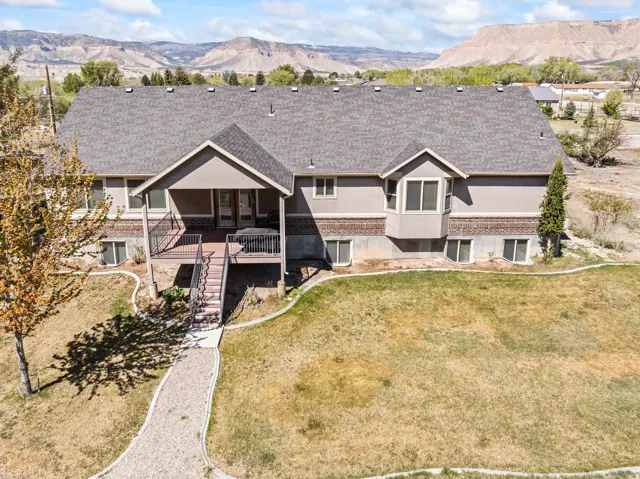 View of front of property with a mountain view, roof with shingles, and brick siding