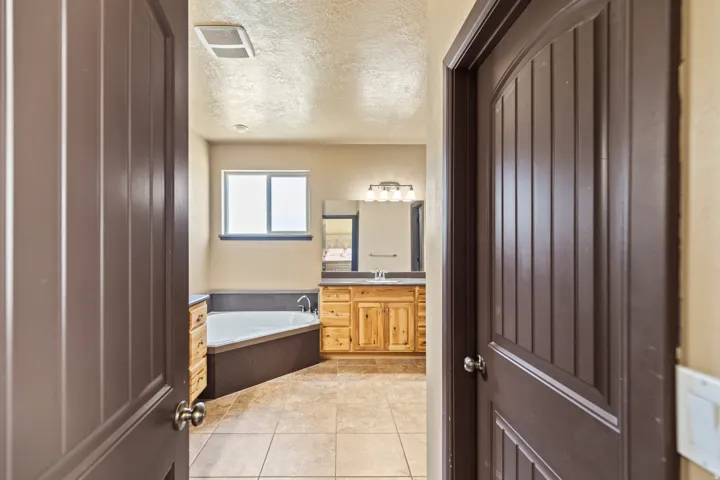Full bath with vanity, a textured ceiling, a bath, and light tile patterned flooring