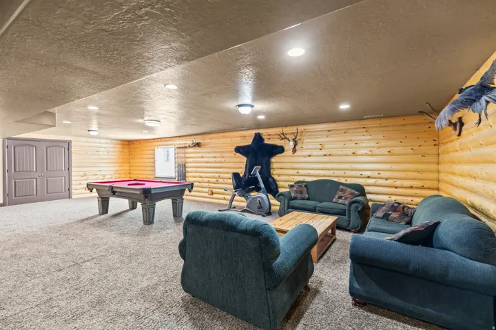 Recreation room with a textured ceiling, rustic walls, carpet, recessed lighting, and billiards table