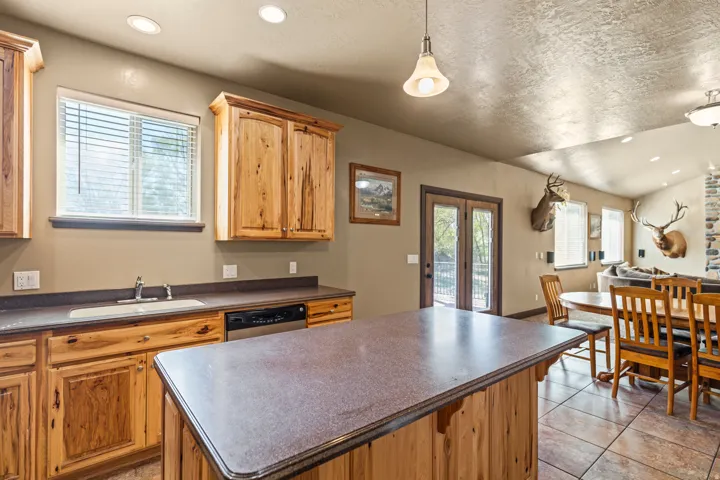 Kitchen with a center island, dark countertops, french doors, hanging light fixtures, and light tile patterned flooring