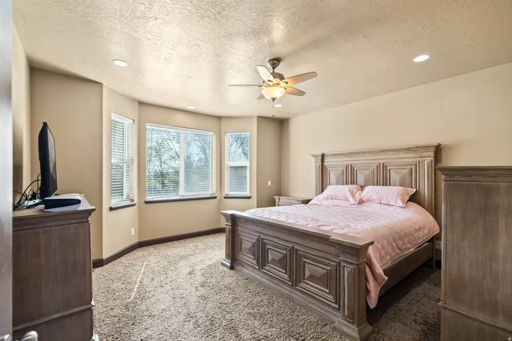 Carpeted bedroom featuring a textured ceiling, recessed lighting, and ceiling fan