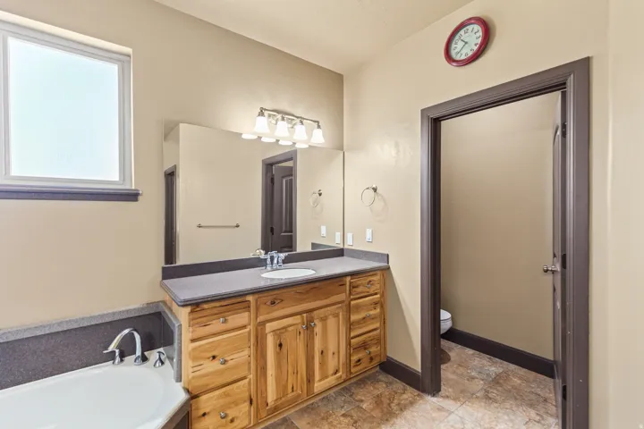 Bathroom featuring vanity, a bath, and stone finish flooring