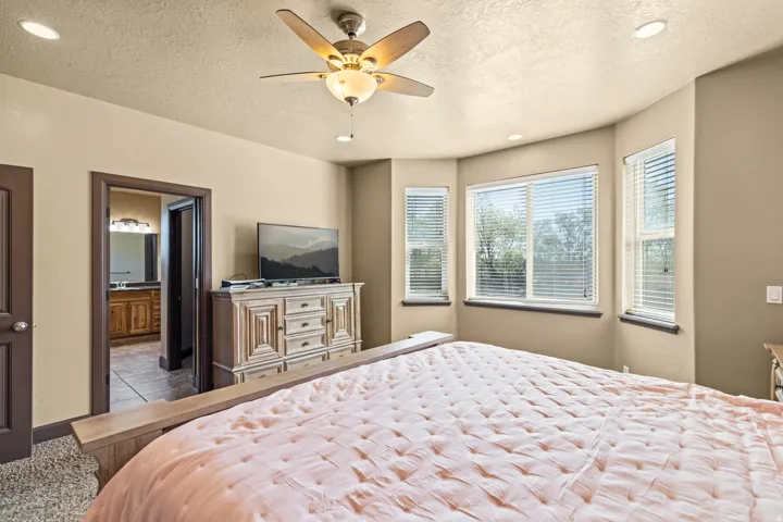 Bedroom featuring recessed lighting, a textured ceiling, a ceiling fan, and ensuite bath