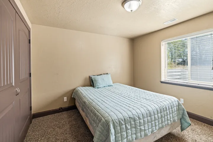 Bedroom featuring a textured ceiling, dark colored carpet, a textured wall, and a closet