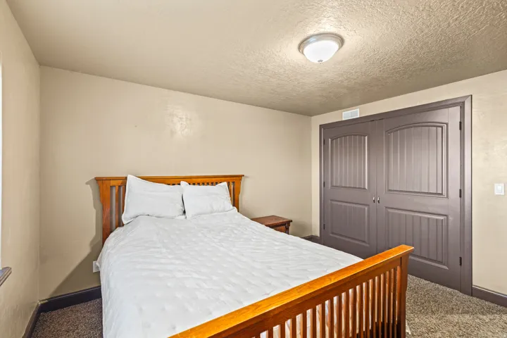 Carpeted bedroom with a textured ceiling and a closet