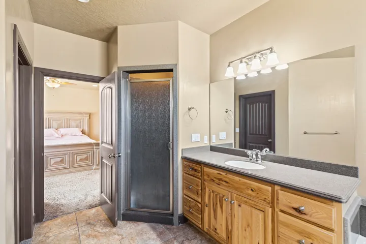 Full bath featuring ensuite bathroom, vanity, a stall shower, a textured ceiling, and ceiling fan