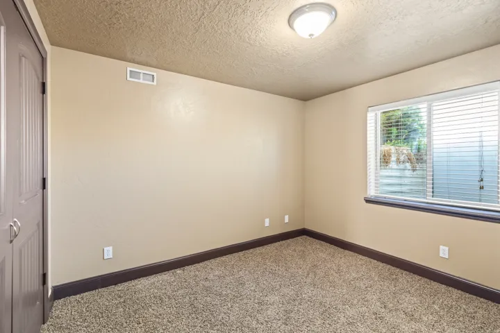 Carpeted empty room featuring a textured ceiling and baseboards