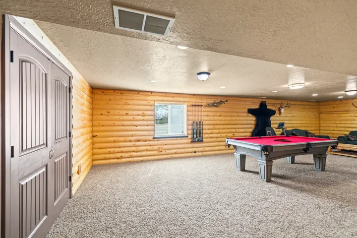 Playroom featuring a textured ceiling, carpet floors, rustic walls, and billiards