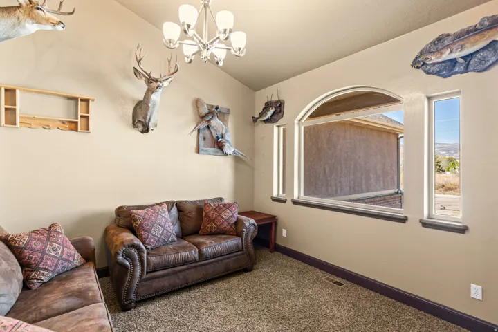 Living room with carpet floors, a chandelier, and lofted ceiling