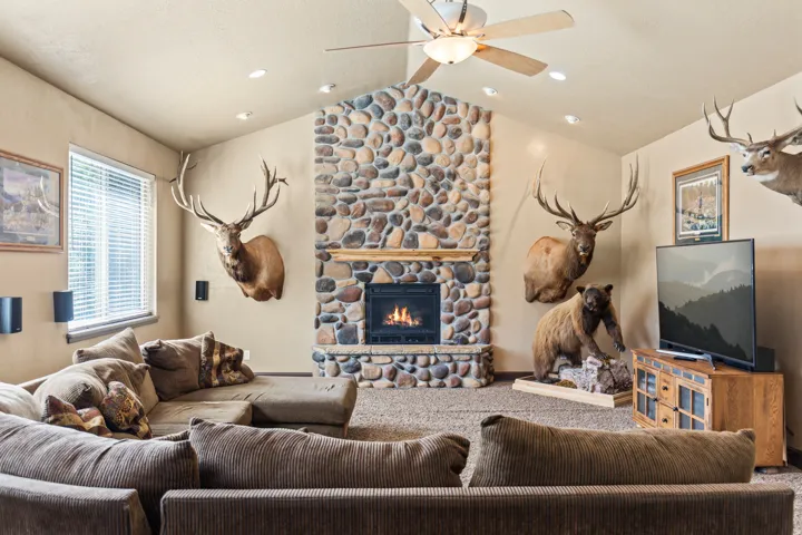 Carpeted living room featuring a fireplace and a ceiling fan