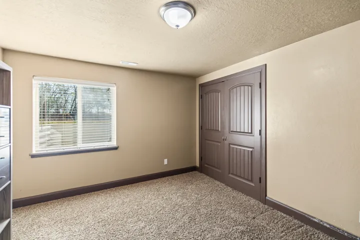 Unfurnished bedroom with a closet, a textured ceiling, and light colored carpet