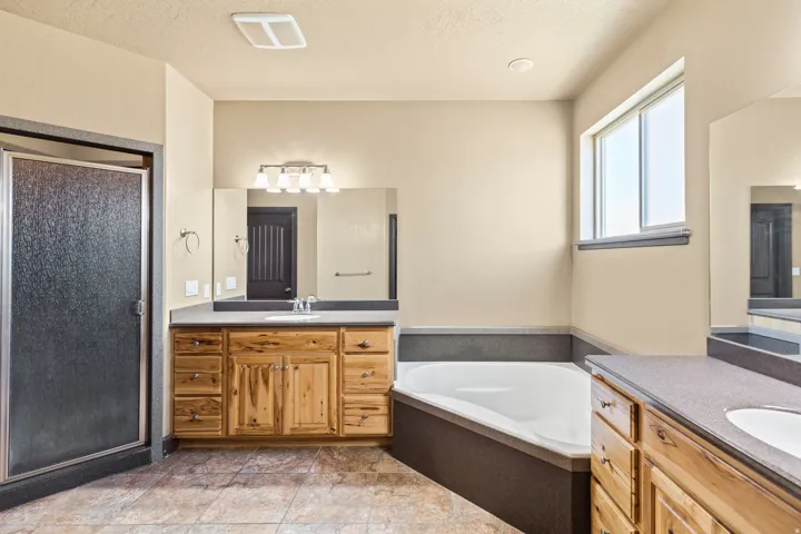 Bathroom with a bath, a stall shower, two vanities, and a textured ceiling