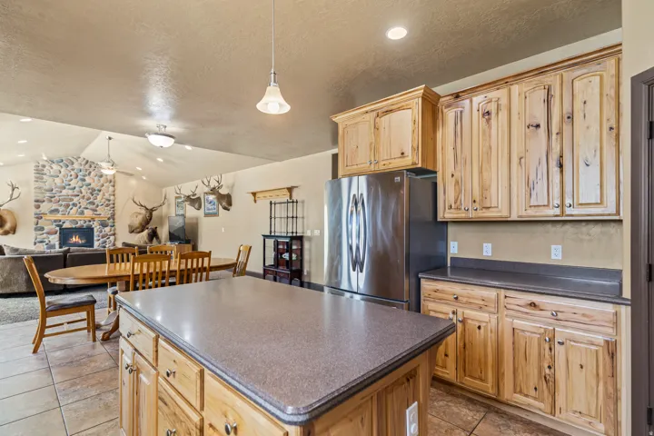 Kitchen with ceiling fan, open floor plan, freestanding refrigerator, a fireplace, and dark countertops