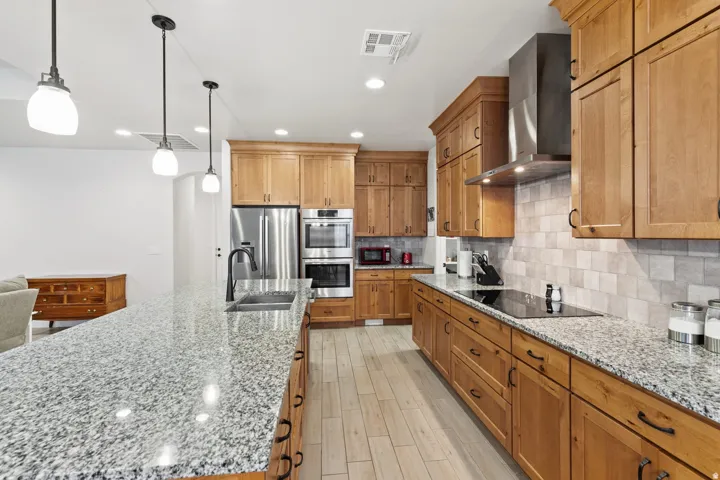 Kitchen with light stone counters, stainless steel appliances, tasteful backsplash, and light wood-type flooring