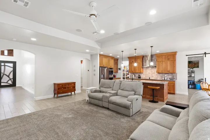 Living area featuring arched walkways, a ceiling fan, a barn door, and recessed lighting